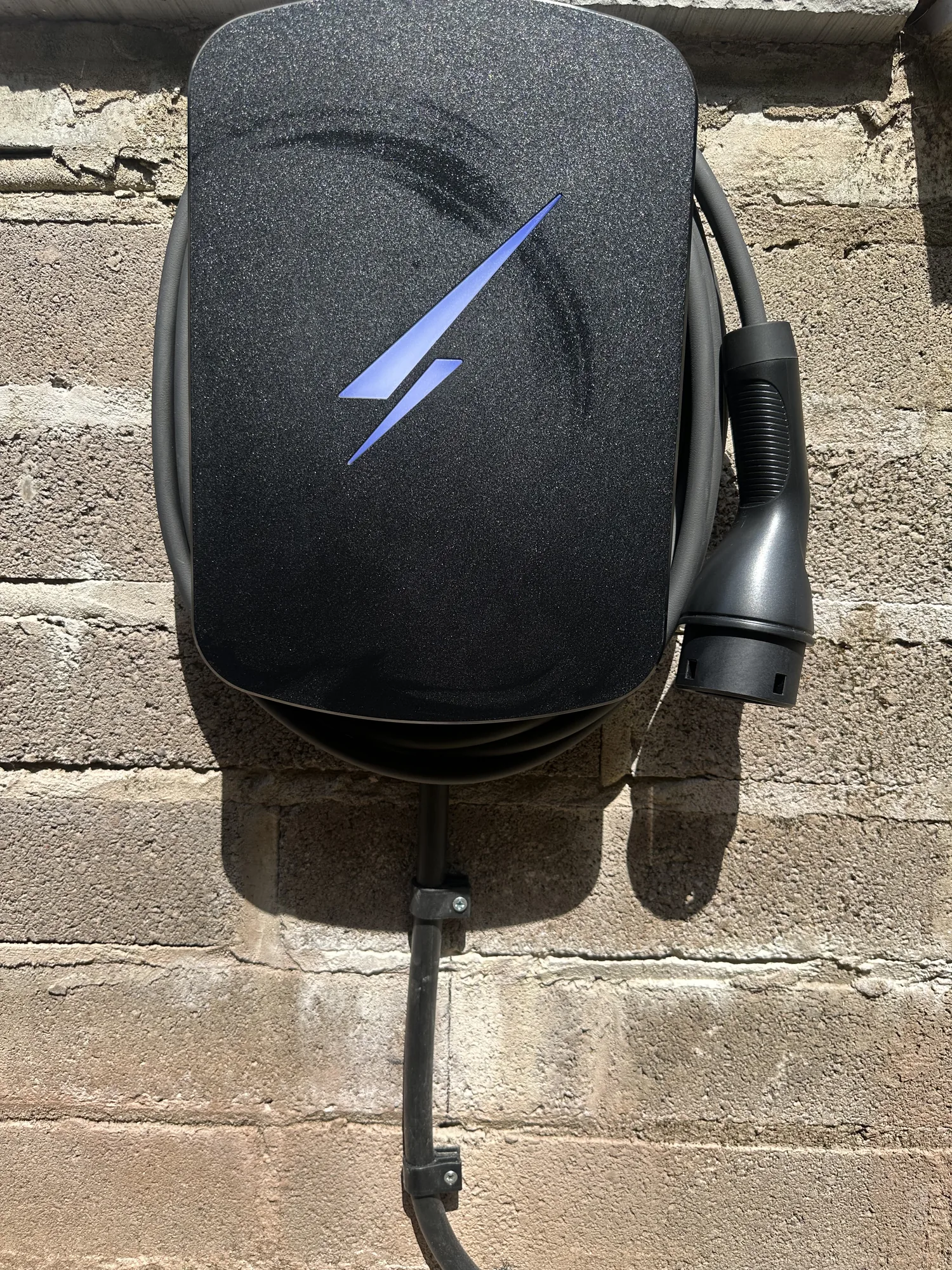 Home EV charger with its Type 2 connector on a brick wall