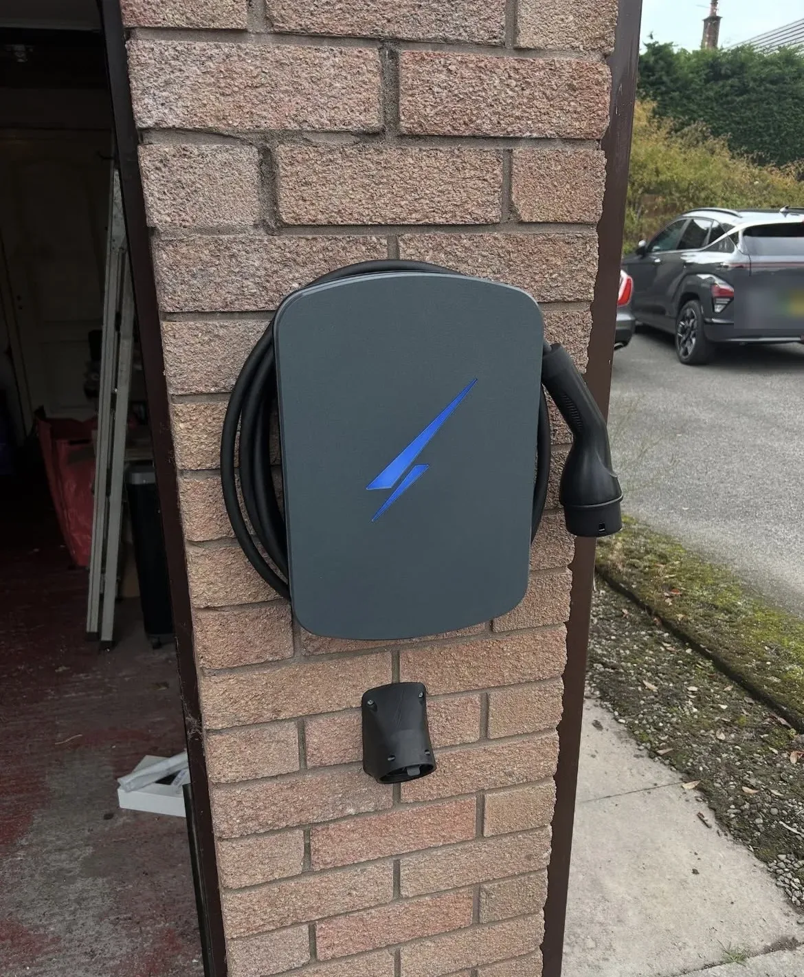 Home EV charger installed with an electric vehicle on the driveway